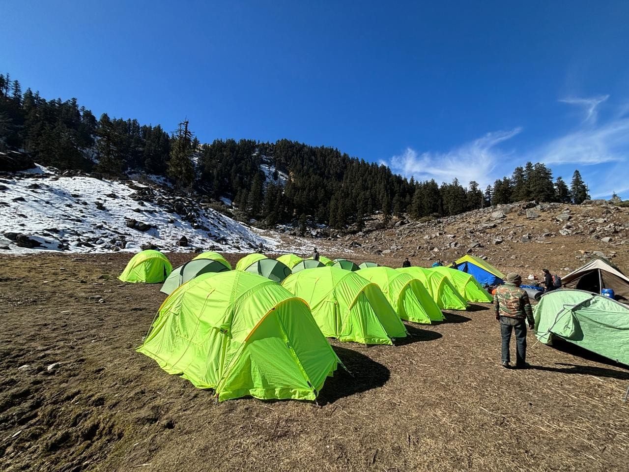 A camp on the shared trail below a snowy slope
